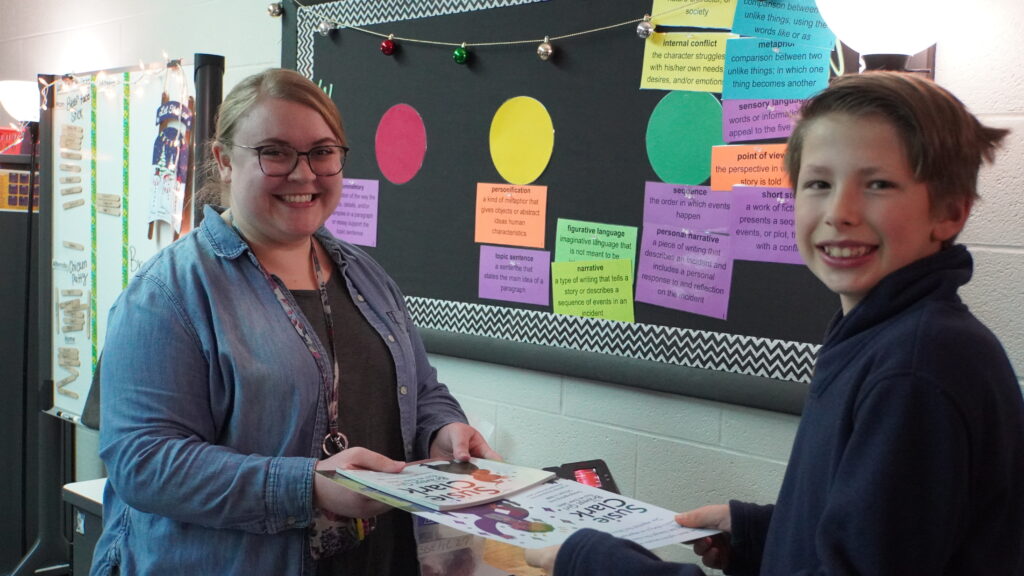 Photo of teacher Taryn Mussehl and student bringing her a copy of the Susie Clark book. 
